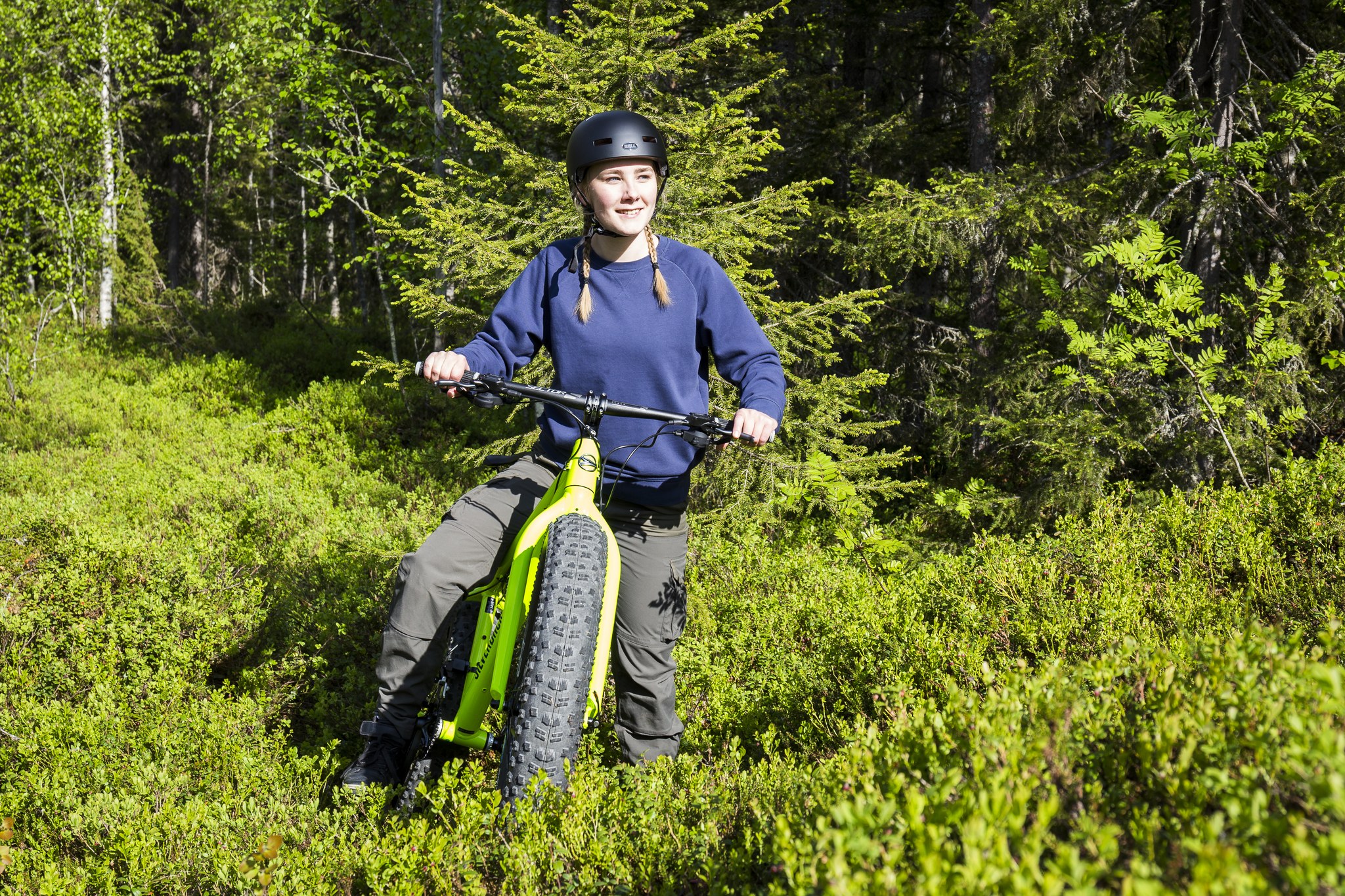 A girl on an e-fat bike in a summer forest taking a break from biking.