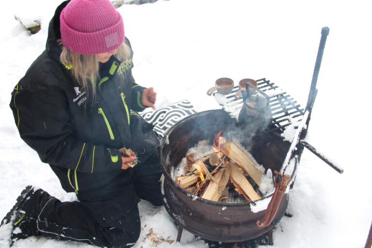 A guide handling a firepit and warming up coffee for the guests.