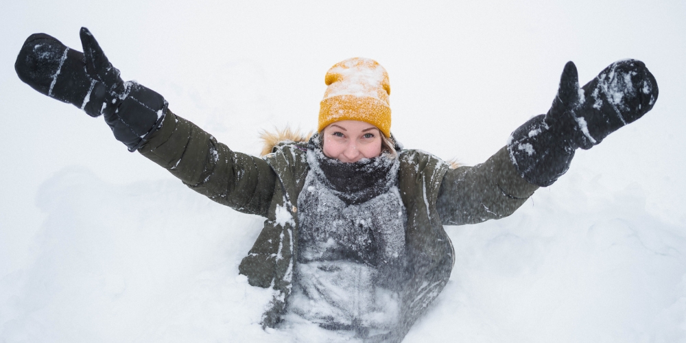 A young woman playing happily in snow.