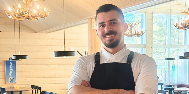 Male restaurant chef smiling confidently at camera.