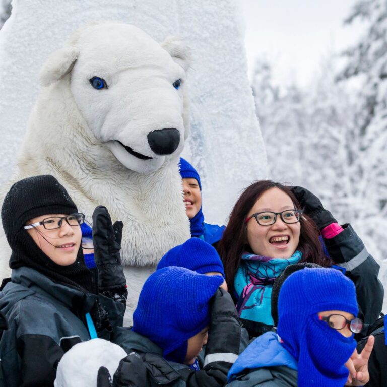 group of international tourists posing with the wildlife park polar bear mascot.