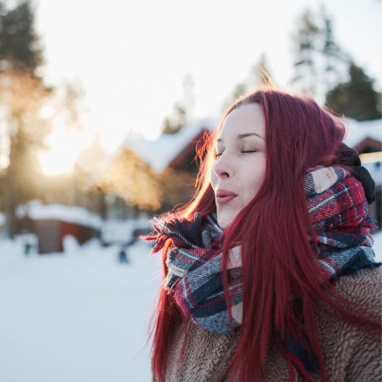A young woman breathing the winter air with eyes closed.